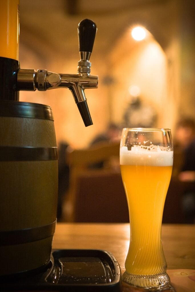 Copa de cerveza al lado de un grifo.