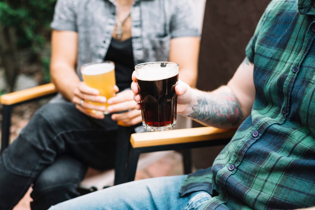 Dos hombres con dos vasos en cerveza en la mano fuera.